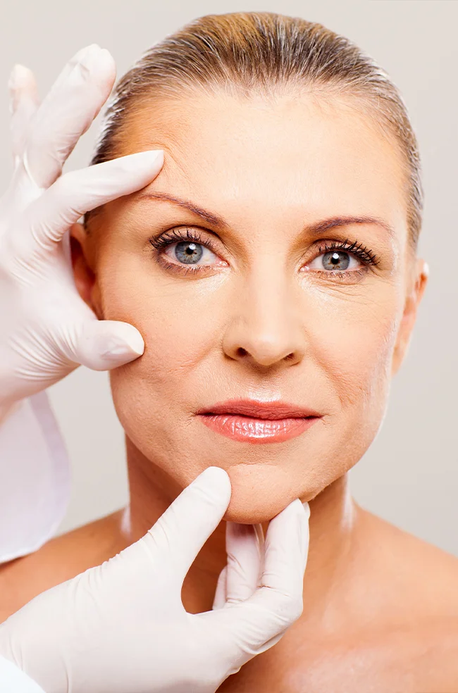 Facial fat transfer: Surgeon examining middle-aged woman’s face for volume restoration procedure