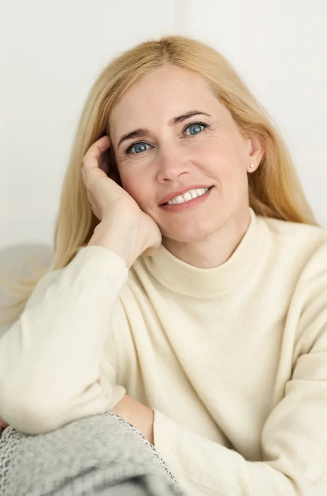 Facial fat transfer: Happy middle-aged woman with smooth skin enjoying natural rejuvenated results