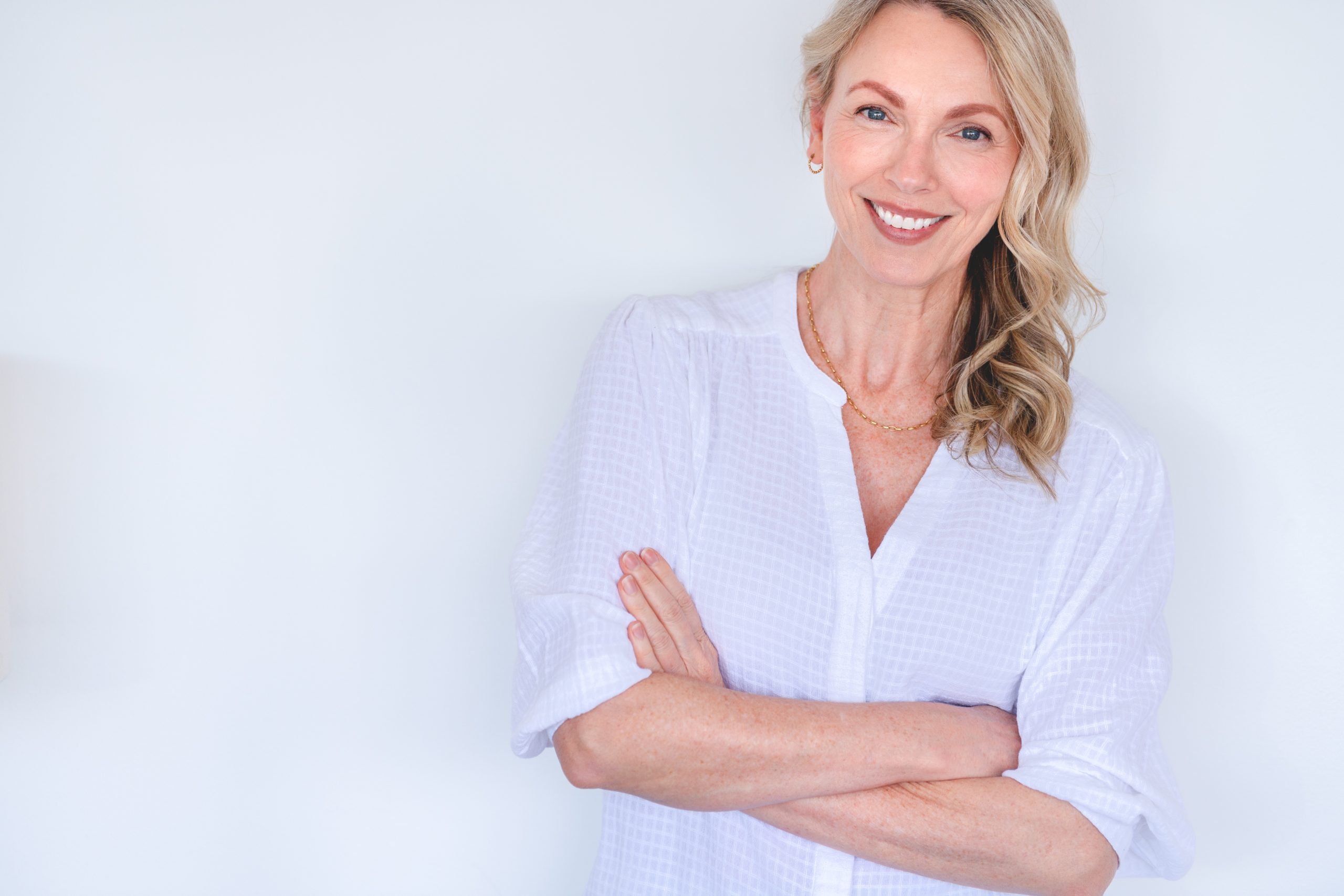 Facial fat transfer: Smiling middle-aged woman with natural youthful appearance in white blouse